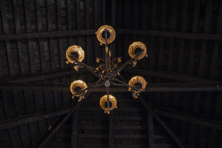 A chandelier hangs from a dark wooden roof.