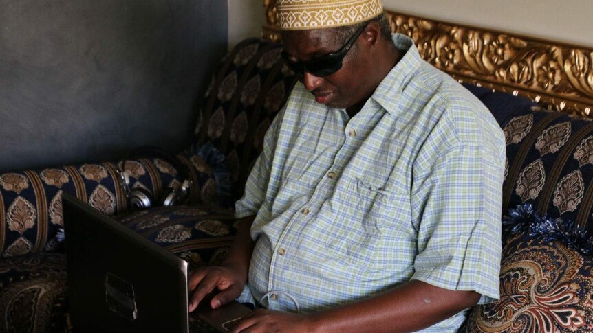 Siyat Abdi sitting in a room with his laptop on his lap.