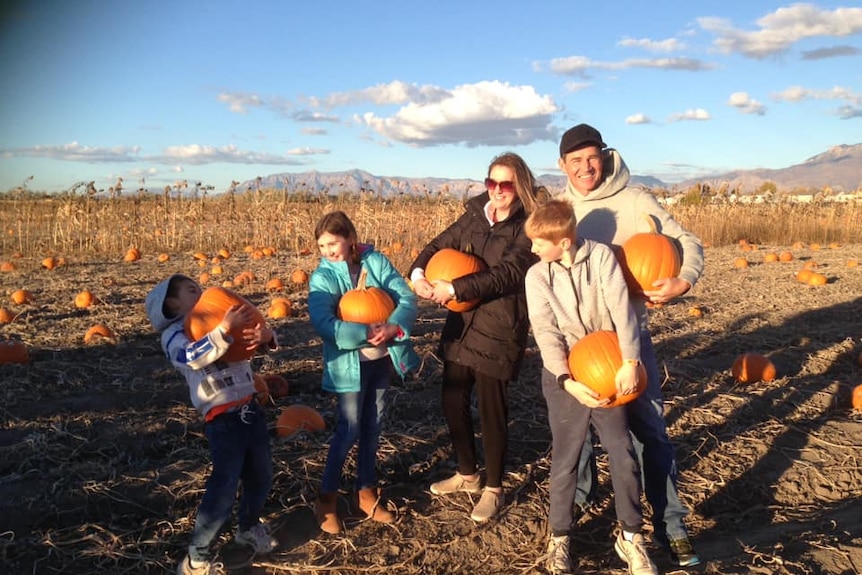 The Allen family holding pumpkins at Halloween in Utah.