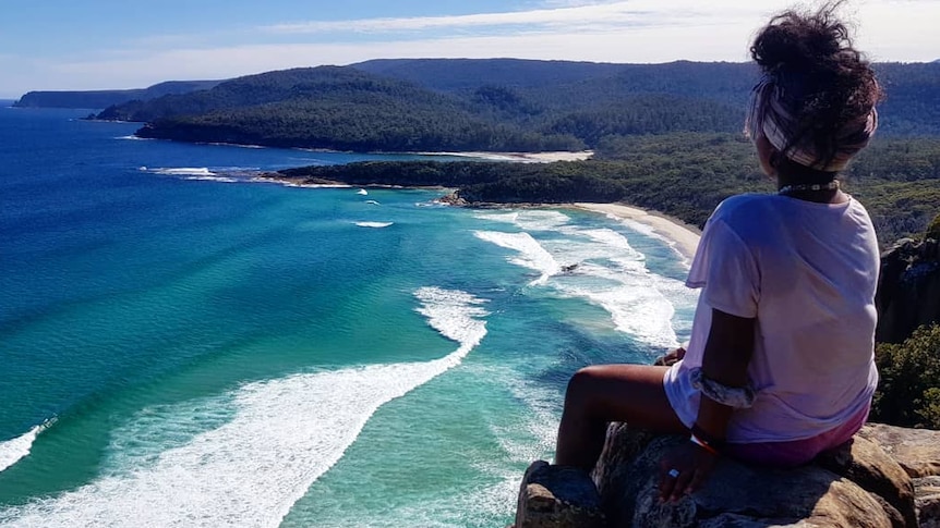 Person looks out across coastline.