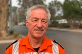 An older man with short light grey hair wearing a bright orange SES jacket. He's looking into the camera.