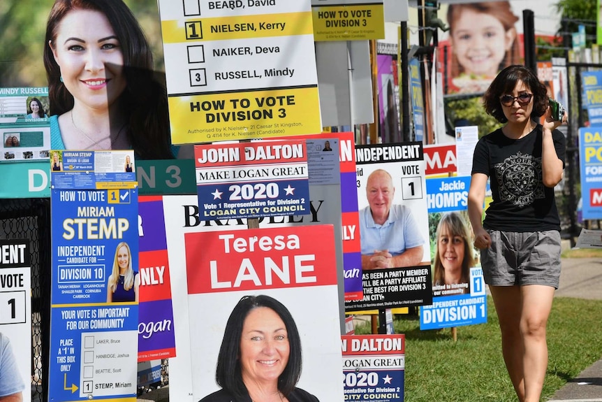 A woman walks past placards with political messages.