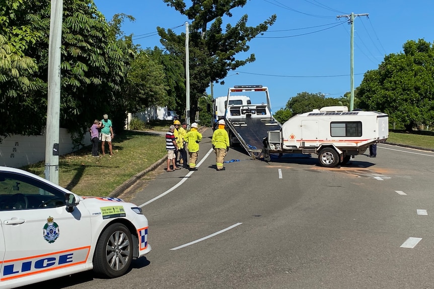 A white caravan being loaded onto a tow truck with police on scene interviewing the owner after it had been stolen. 