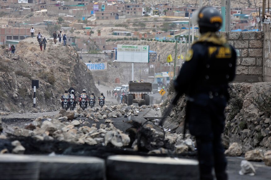 Rocks block a highway in Peru as police arrive to clear the roadblock.