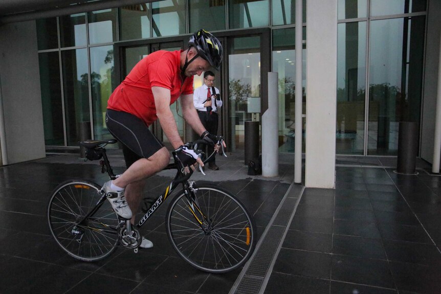 Liberal MP Andrew Wallace gets on his bike outside Parliament House.