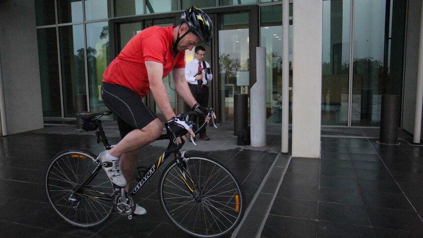 Liberal MP Andrew Wallace gets on his bike outside Parliament House.