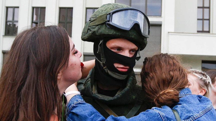 Women embrace a soldier guarding the Belarusian Government building, in an exaggerated show of friendliness.