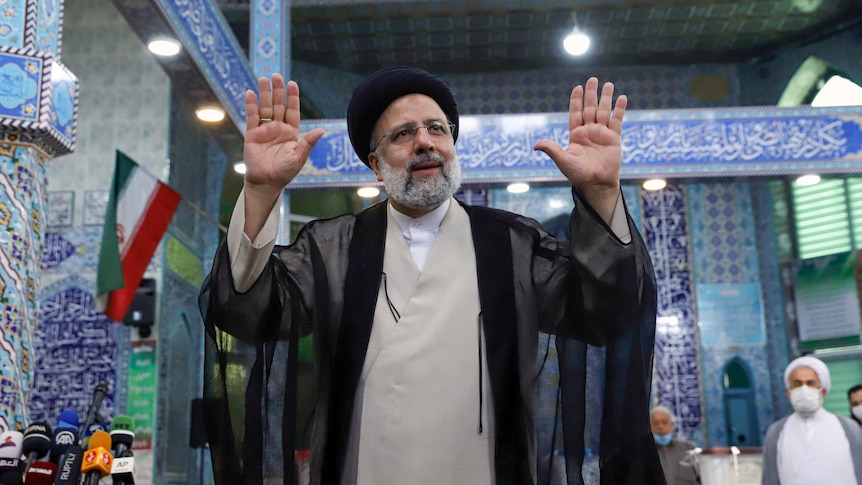 Hardliner Ebrahim Raisi gestures with arms up and palms outward after voting during the election on June 18.