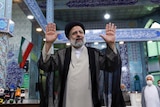 Hardliner Ebrahim Raisi gestures with arms up and palms outward after voting during the election on June 18.
