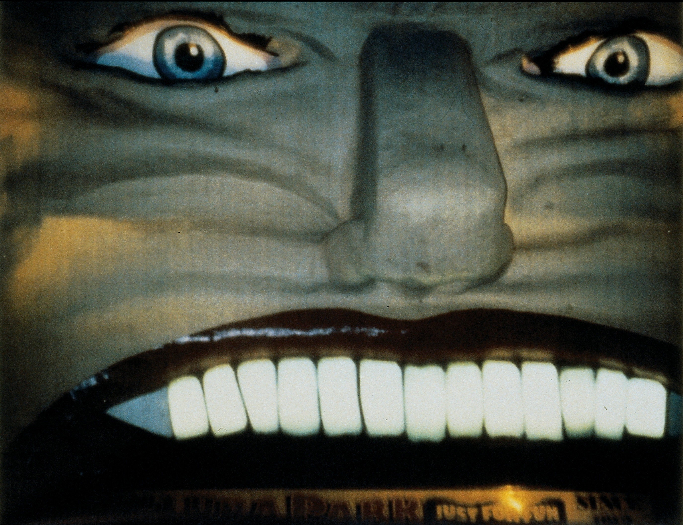 A 90s photograph of a sculpted face with white teeth, big eyes and nose, the old entrance to Melbourne's Luna Park