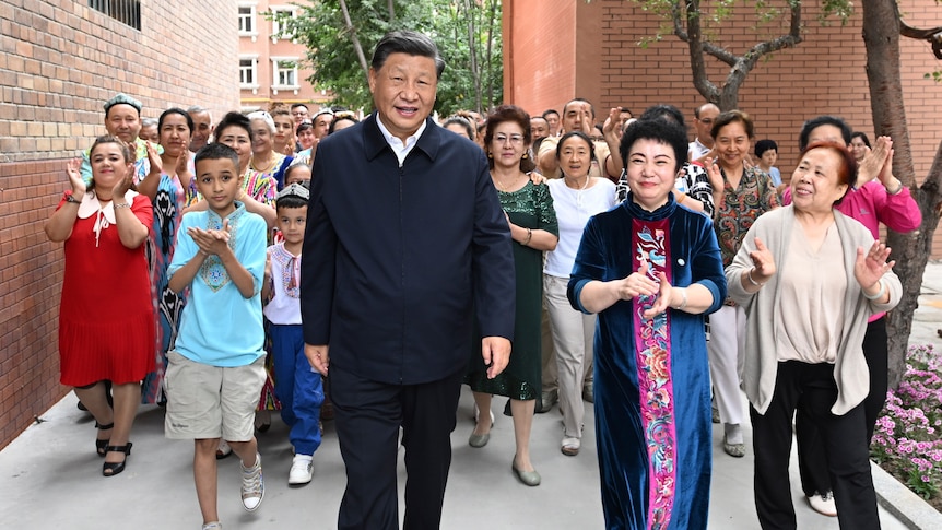 Xi Jinping walks, surrounded by people clapping