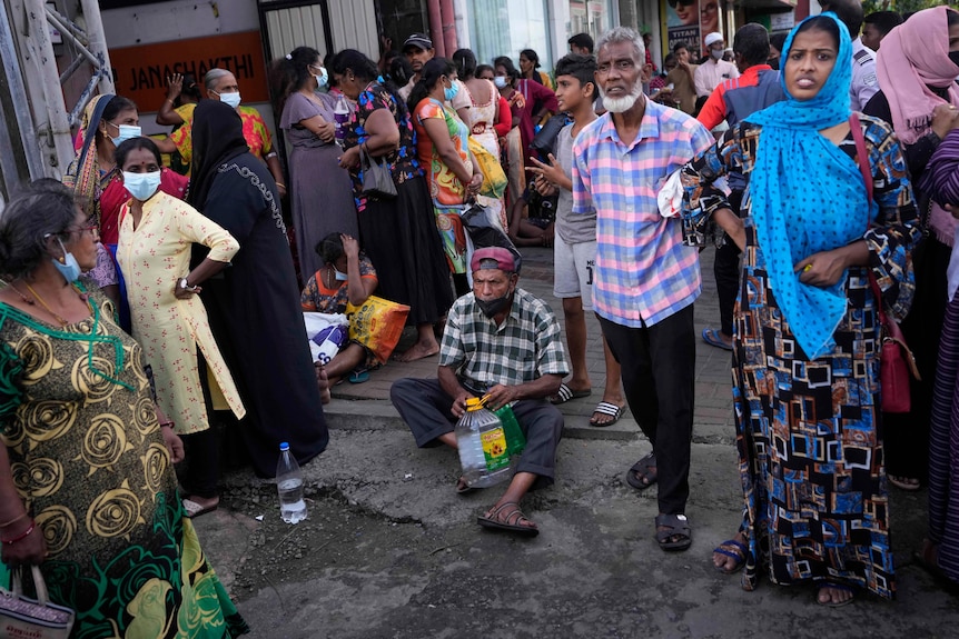 Dozens of men and women wait in a queue to buy kerosene