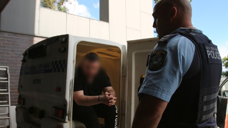 A man sitting in the back of a police van.