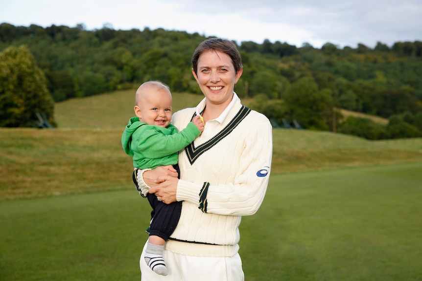 Sarah Elliot holds her son Sam while in her cricket whites.