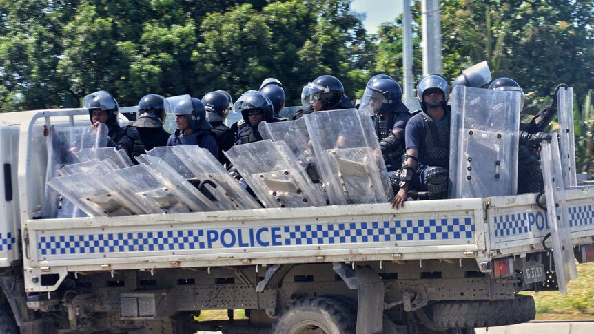 Riot police ride in the back of a truck as they are deployed in Honiara.