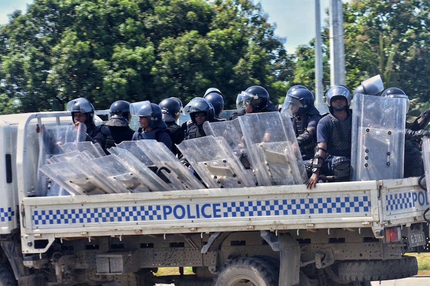 Riot police ride in the back of a truck as they are deployed in Honiara.