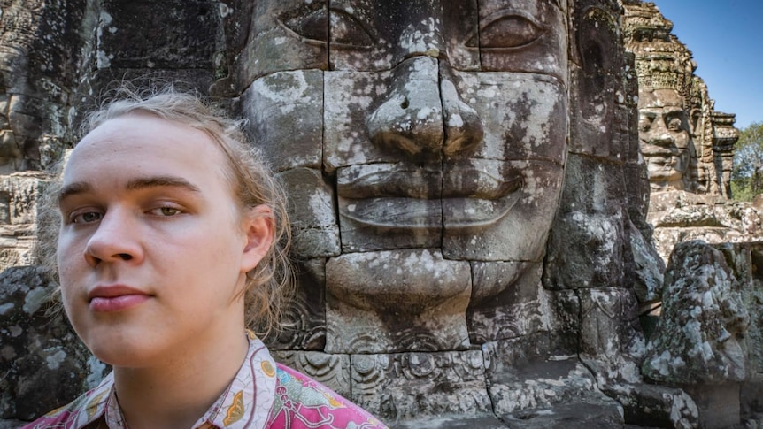 A teenager poses in front of an ancient Cambodian temple.