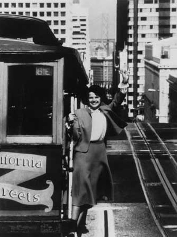 A young woman waves from a San Francisco cable car 