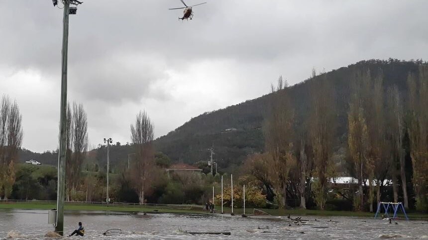 Helicopter hovers overhead of boy trapped in flood water.