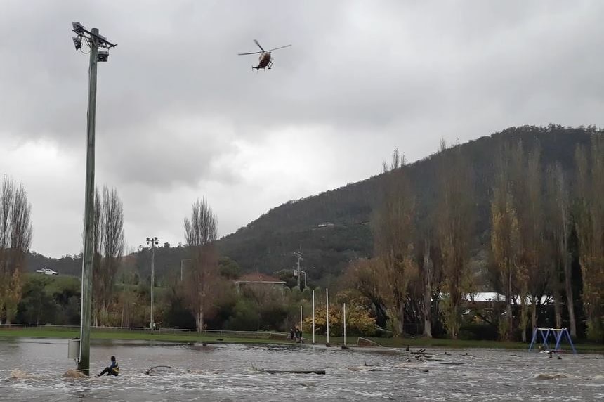 Helicopter hovers overhead of boy trapped in flood water.