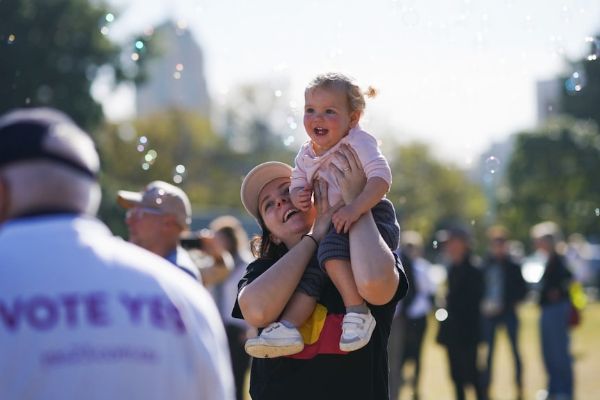 A young girl smiles at bubbles blowing around the Come Together For Yes rally in Sydney