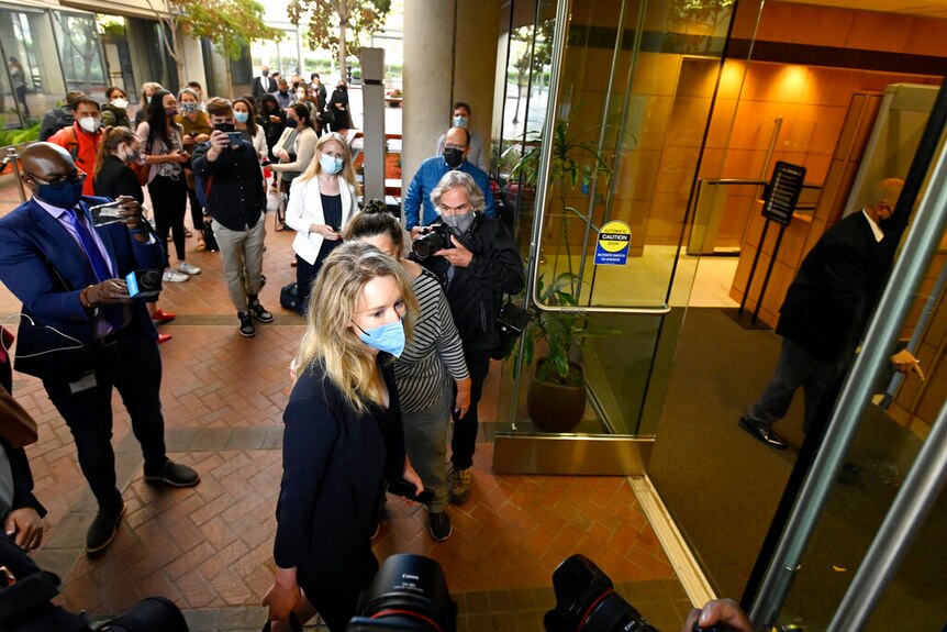 Elizabeth Holmes enters a court building surrounded by media.