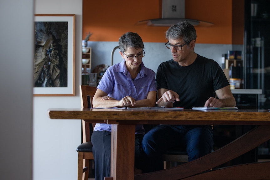 Man and woman sitting at a dining table with documents in front of them.