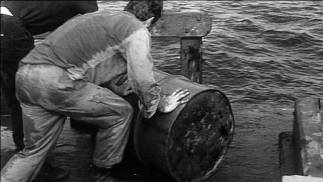 Man pushes barrel on boat deck