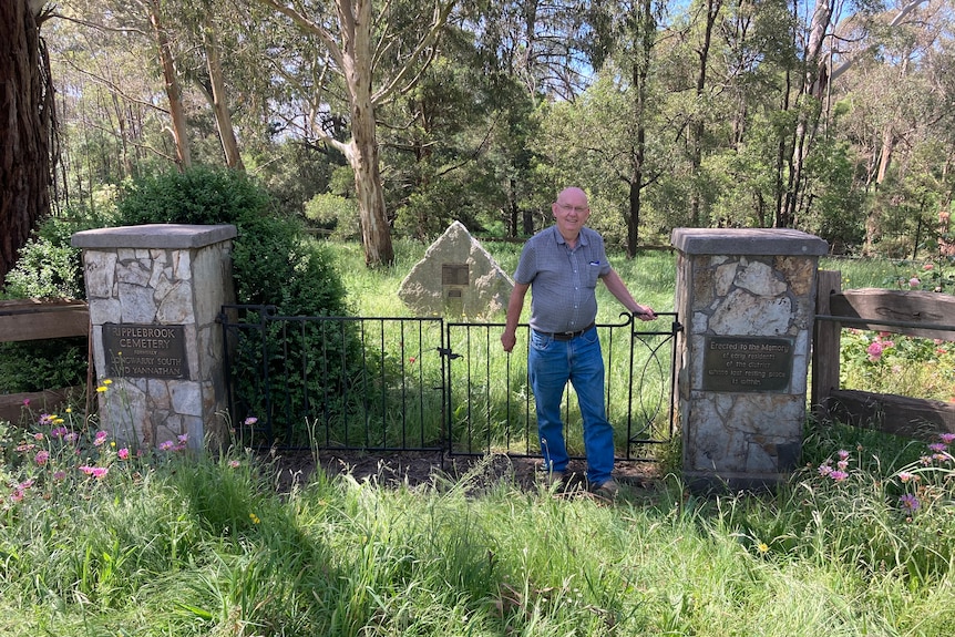 Terry Handley stands next to memorial gates  at the entrance to the Ripplebrook cemetery. 