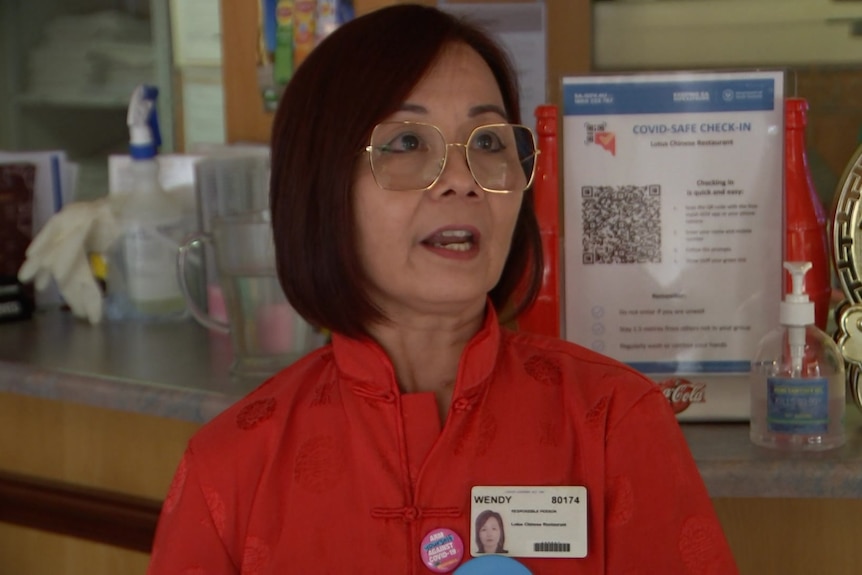 Una mujer de pelo negro y gafas con un top rojo.