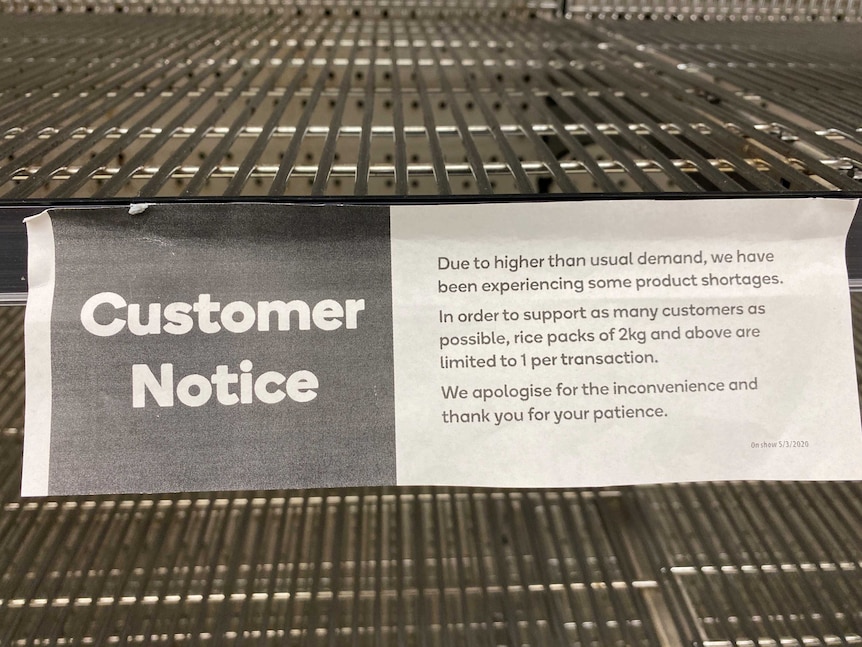 A sign on an empty supermarket shelf that reads rice is limited to 2kg per customer