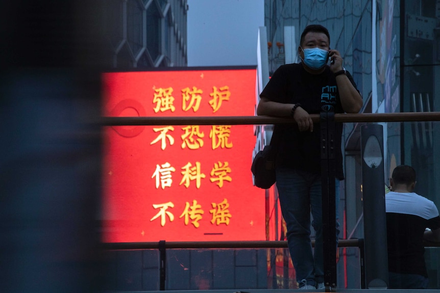 La letra china dice en rojo y amarillo: "Reforzar la protección, no entrar en pánico, creer en la ciencia, no difundir rumores"