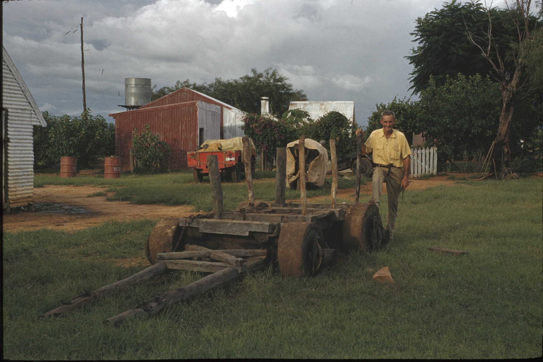 a man stands next to a low wooden wagon