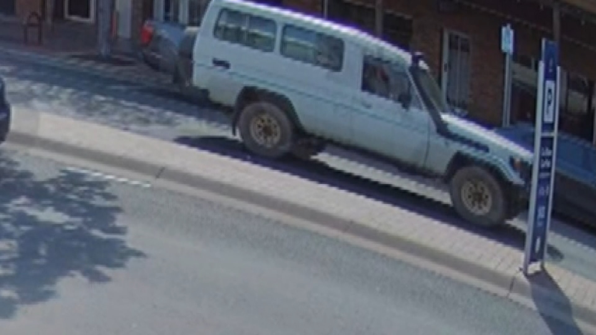 A white SUV drives on a road 