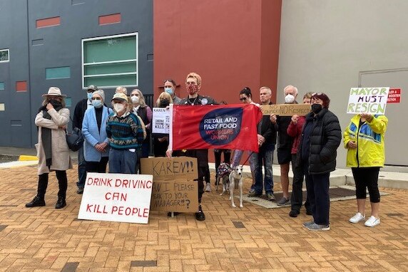 A group of people with protest signs.  'Drink driving can kill people'.