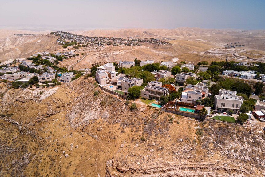 A drone view from above of a residential neighbourhood built on top of a mountain surrounded by arid land