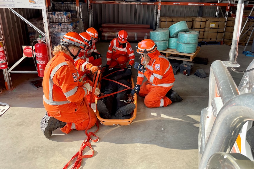 five women preparing to lift a stretcher