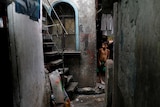 A little boy stands in a dark alleyway.