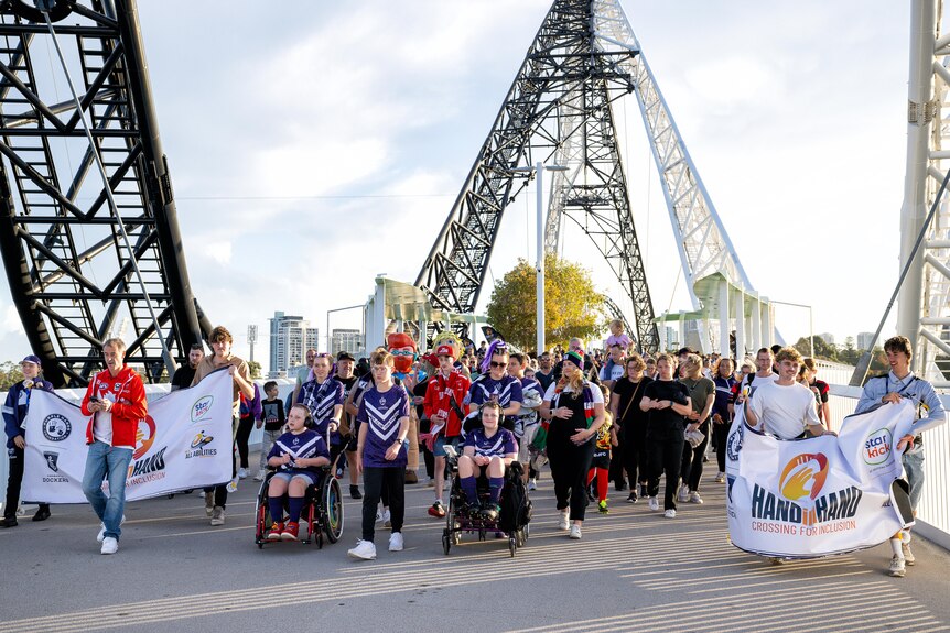 Dozens of people made their way across a large bridge in Perth holding banners and wearing football uniforms