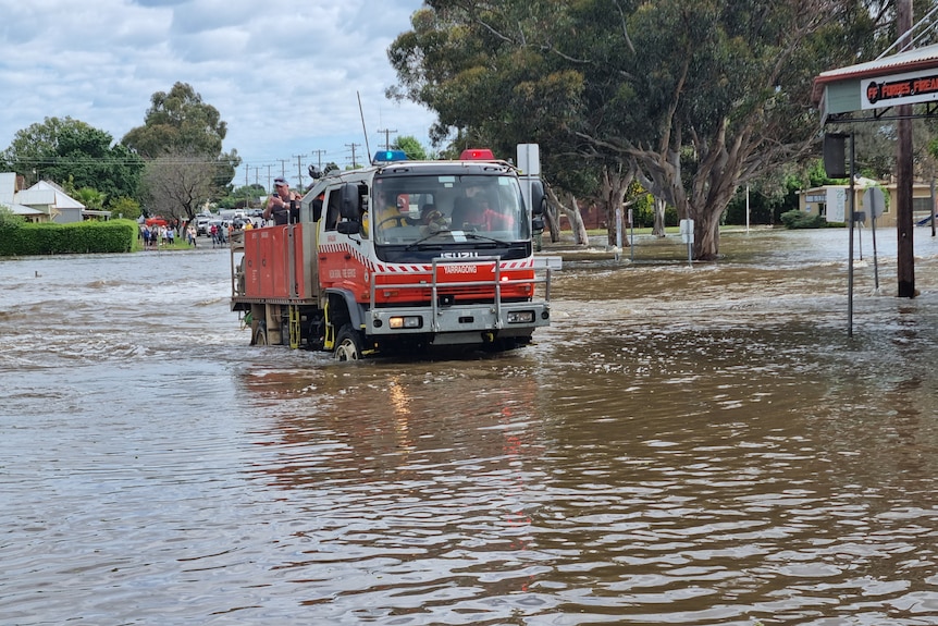 An emergency service truck transports residents through floodwaters in a country town.