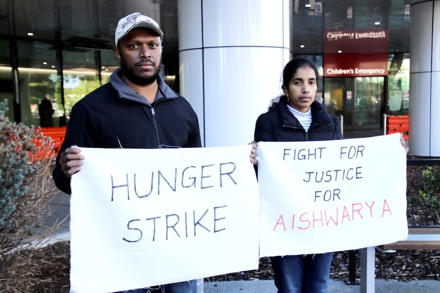 A photo of a man and a woman holding signs that say 'fight for justice' and 'hunger strike'.