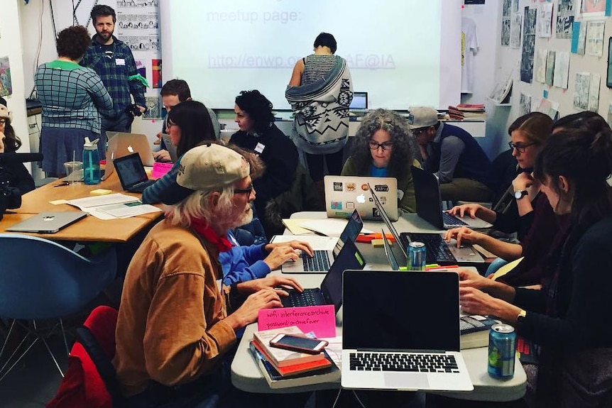 A group of men and women work at computers as part of a Wikipedia edit-a-thon.