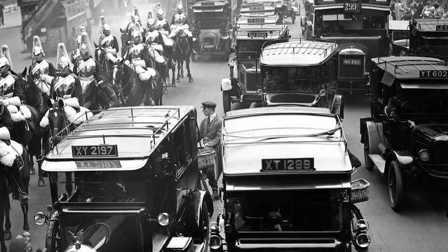 Photo of old cars on street beside mounted Royal Guard