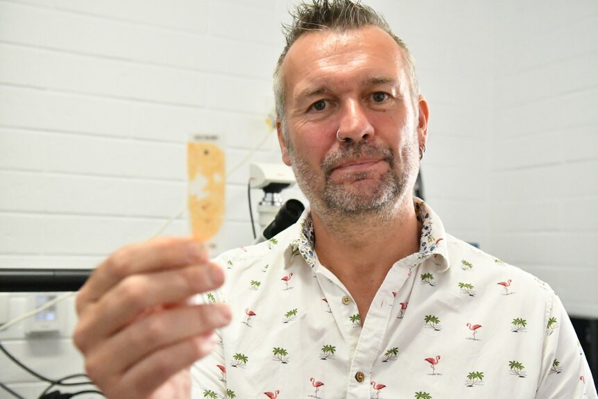 A man holding up a microscope slide