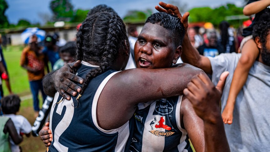 To Muluwurri Magpies players embrace and celebrate.