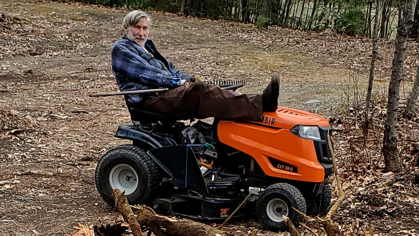 Geoffrey Holt rests his leg on top of his riding mower.