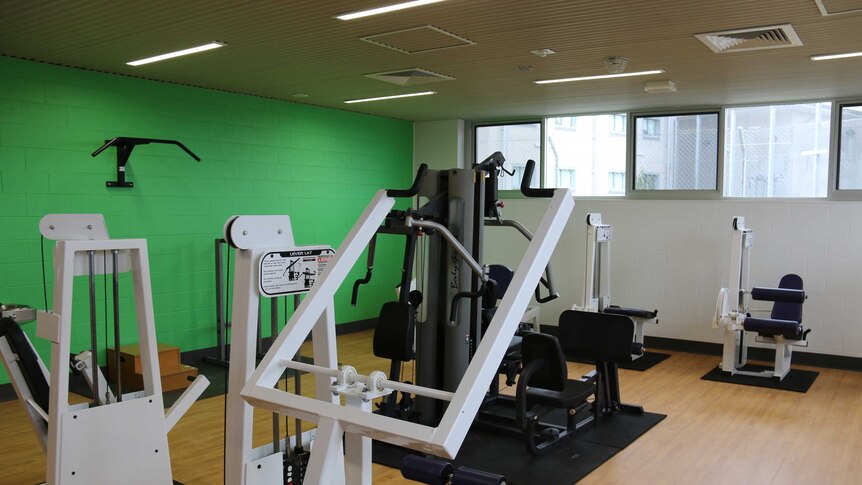 Gym equipment in a new room with a green wall at Canberra's jail