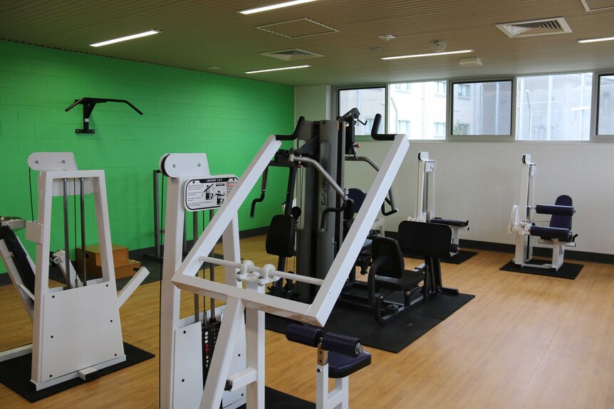 Gym equipment in a new room with a green wall at Canberra's jail