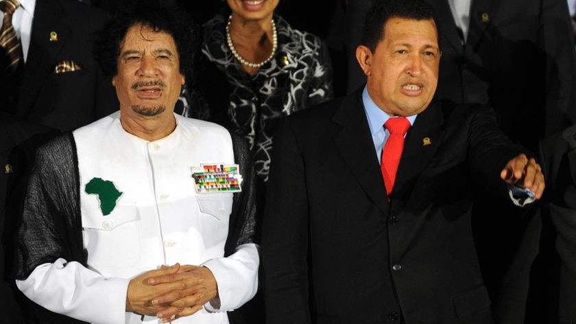 Venezuela's President Hugo Chavez (C) and Libyan leader Moamar Gaddafi wave to the crowd