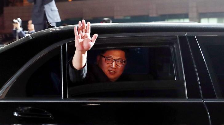Kim Jong-un waves and smiles from the window of a car